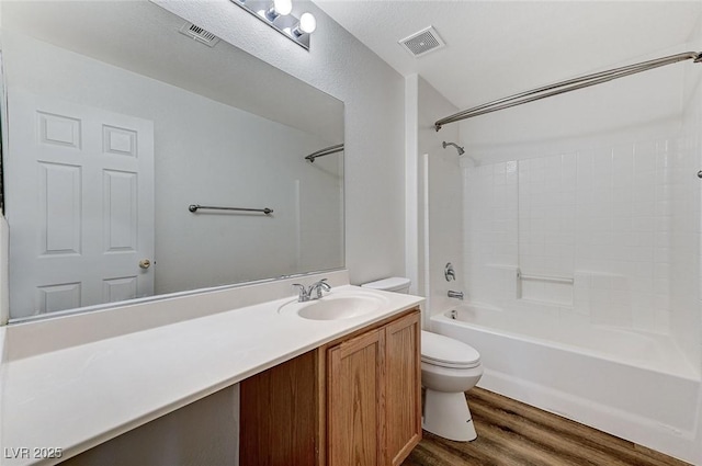 bathroom featuring toilet, wood finished floors, vanity, and shower / bathtub combination