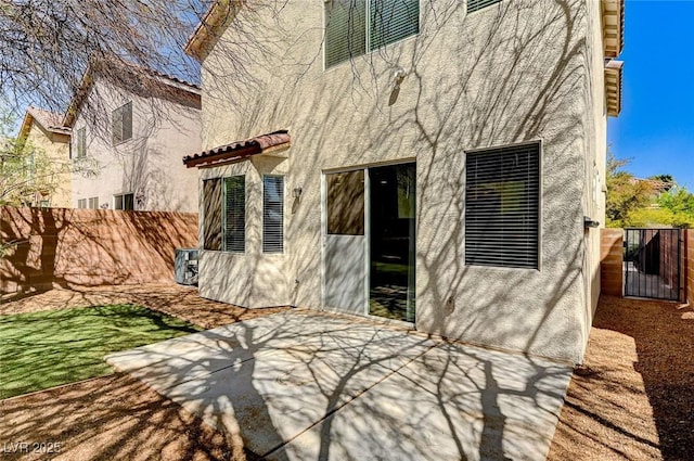 rear view of house featuring stucco siding, a patio, fence, and a tiled roof