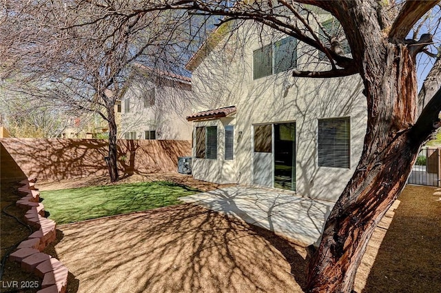 rear view of property featuring stucco siding, a fenced backyard, and a patio area