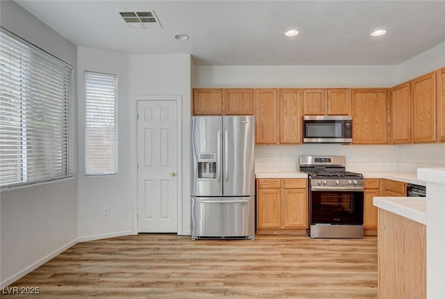 kitchen with stainless steel appliances, light wood finished floors, plenty of natural light, recessed lighting, and light countertops