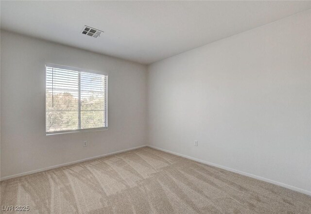 empty room featuring light carpet and baseboards