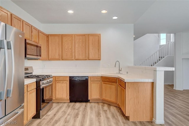 kitchen with appliances with stainless steel finishes, a sink, light wood-style floors, a peninsula, and recessed lighting