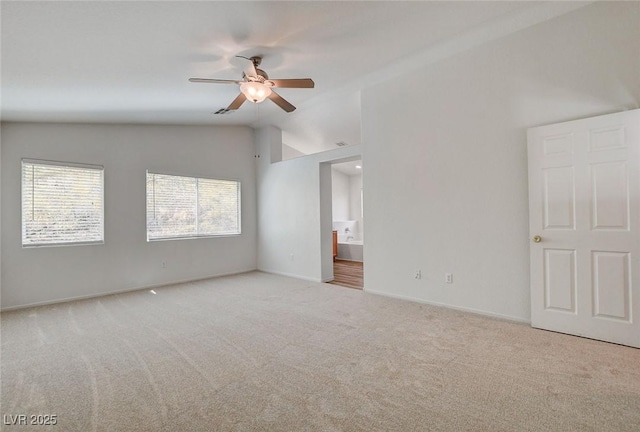 unfurnished bedroom featuring vaulted ceiling, carpet, ensuite bathroom, baseboards, and a ceiling fan