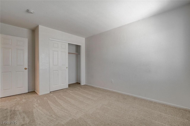 unfurnished bedroom featuring light colored carpet, a closet, and baseboards