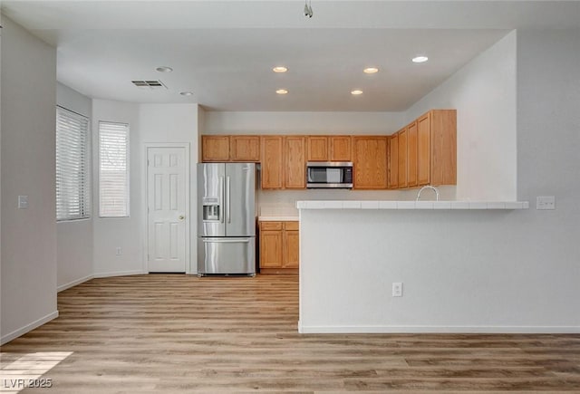 kitchen featuring appliances with stainless steel finishes, recessed lighting, light wood-style flooring, baseboards, and light countertops