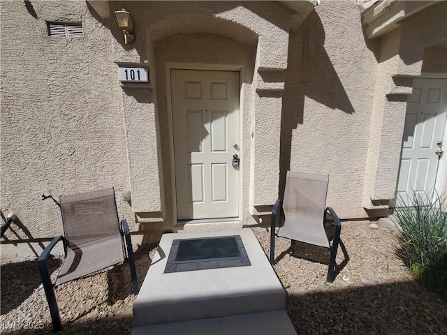 doorway to property featuring stucco siding