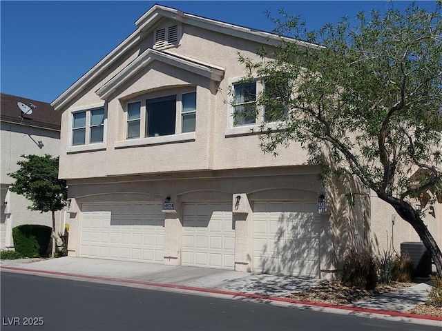 view of front of property with an attached garage, stucco siding, and central AC