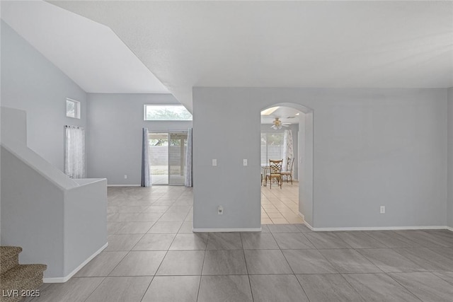 8005 Exploration Ave, Las Vegas, NV 89131 - spare room with tile patterned flooring, vaulted ceiling, arched walkways, baseboards, and stairs