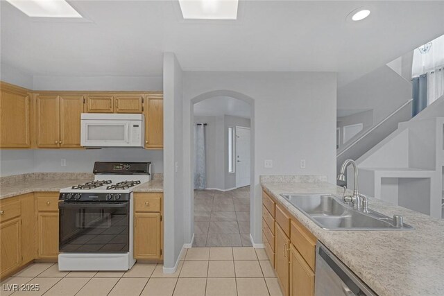 8005 Exploration Ave, Las Vegas, NV 89131 - kitchen with light tile patterned floors, arched walkways, a sink, gas stove, and white microwave