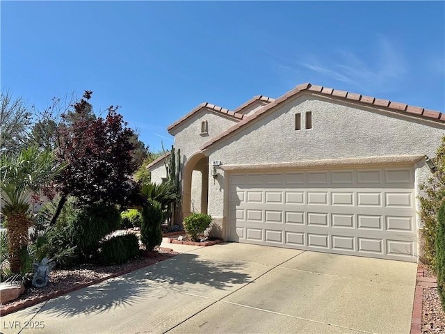 view of front facade with stucco siding, concrete driveway, an attached garage, and a tile roof