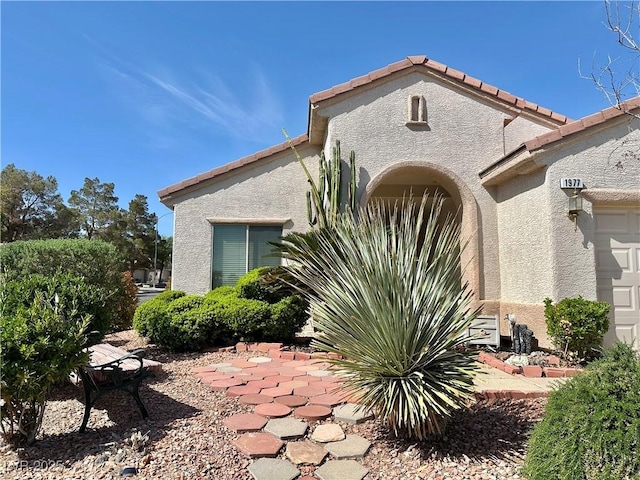exterior space featuring stucco siding, a tiled roof, a patio, and an attached garage