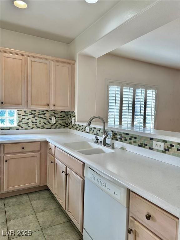 kitchen featuring a sink, white dishwasher, tasteful backsplash, and light brown cabinets
