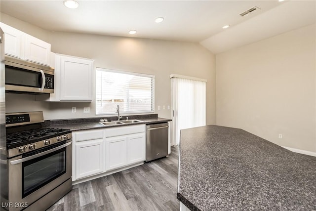 3434 Denali Preserve St, Las Vegas, NV 89122 - kitchen featuring vaulted ceiling, white cabinetry, dark countertops, stainless steel appliances, and a sink