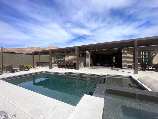 view of pool with a pool with connected hot tub, fence, a patio, and outdoor dry bar