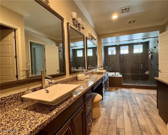 full bathroom with a shower stall, visible vents, wood finished floors, a sink, and double vanity
