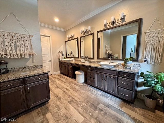 full bathroom with a sink, ornamental molding, double vanity, and wood finished floors