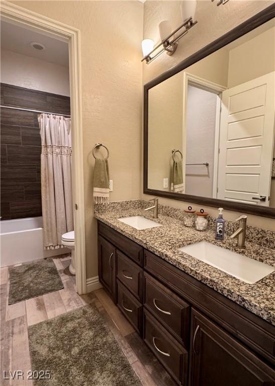 bathroom with a sink, toilet, double vanity, and wood finished floors