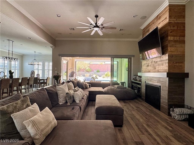 living area with ceiling fan with notable chandelier, a fireplace, visible vents, recessed lighting, and dark wood-style floors