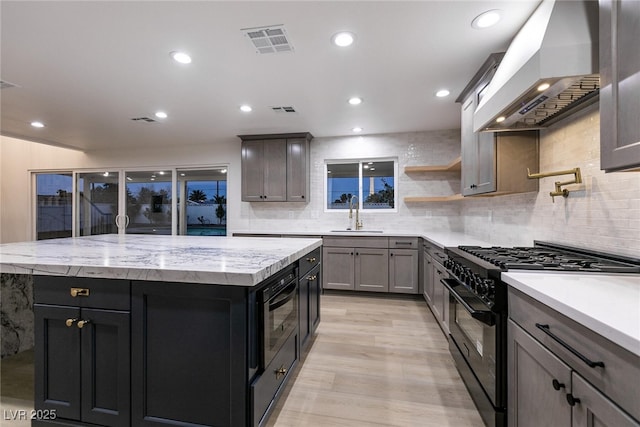 kitchen featuring a center island, high end black range, a sink, wall chimney range hood, and built in microwave