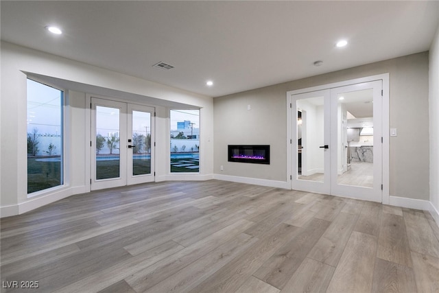 unfurnished living room featuring light wood-type flooring, french doors, visible vents, and recessed lighting