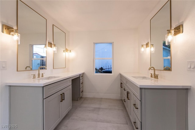 full bath featuring two vanities, baseboards, and a sink