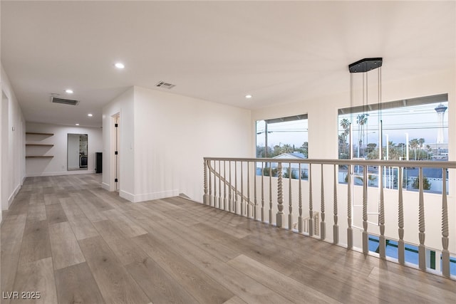 hall featuring wood finished floors, baseboards, visible vents, and recessed lighting