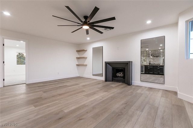 unfurnished living room with light wood finished floors, a fireplace, a ceiling fan, and recessed lighting