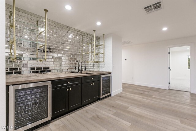 bar with indoor wet bar, a sink, beverage cooler, and visible vents