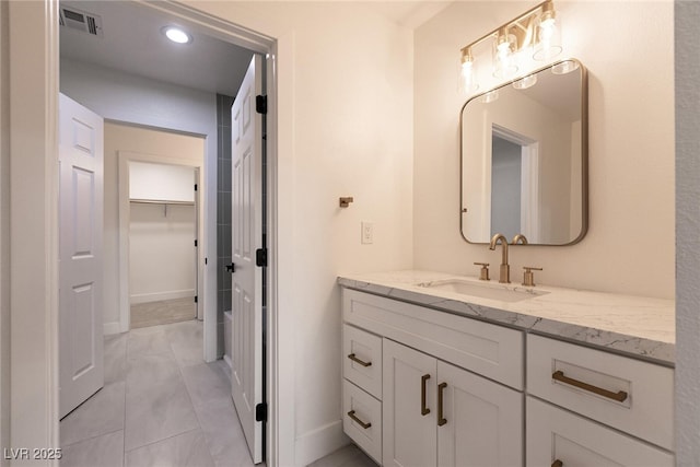 bathroom with visible vents, baseboards, a spacious closet, recessed lighting, and vanity