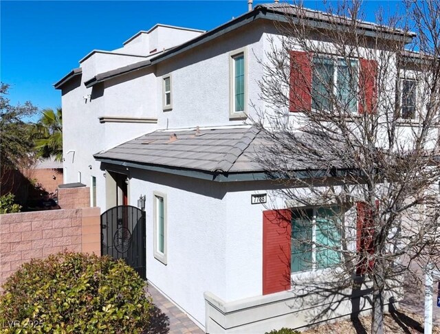 view of property exterior with stucco siding, a gate, and fence