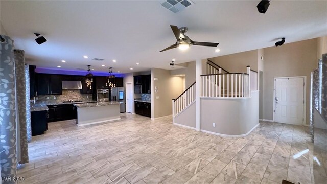 kitchen with under cabinet range hood, stainless steel appliances, backsplash, open floor plan, and recessed lighting