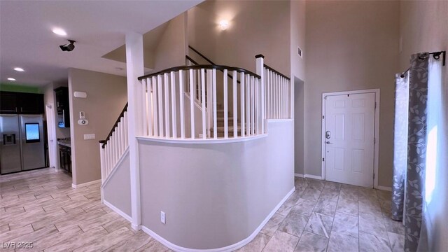 staircase featuring baseboards, a high ceiling, and recessed lighting