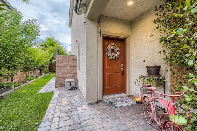 property entrance with stucco siding, fence, and a patio
