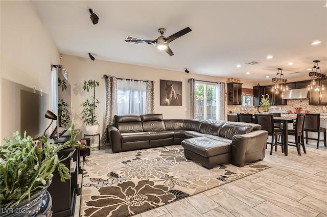 living area with a ceiling fan, a chandelier, and recessed lighting
