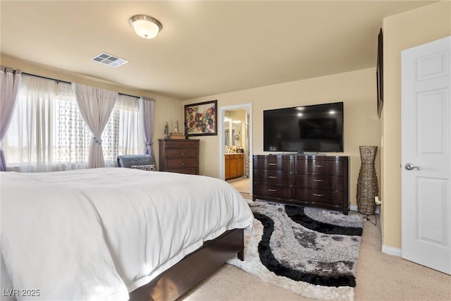bedroom featuring light carpet, visible vents, baseboards, and ensuite bathroom