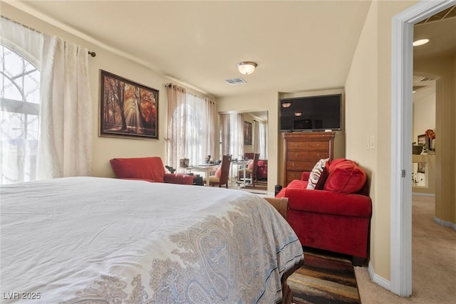 carpeted bedroom featuring visible vents, baseboards, and multiple windows