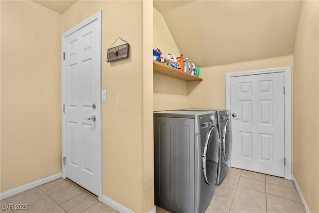 washroom with baseboards, washing machine and dryer, light tile patterned flooring, and laundry area