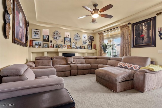 living area with a fireplace, carpet, and a ceiling fan