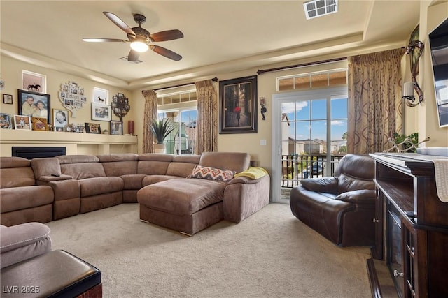 living area featuring a ceiling fan, a fireplace, carpet, and visible vents