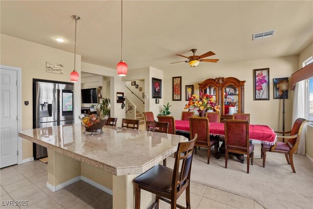 kitchen with stainless steel fridge with ice dispenser, a breakfast bar, light tile patterned floors, open floor plan, and visible vents