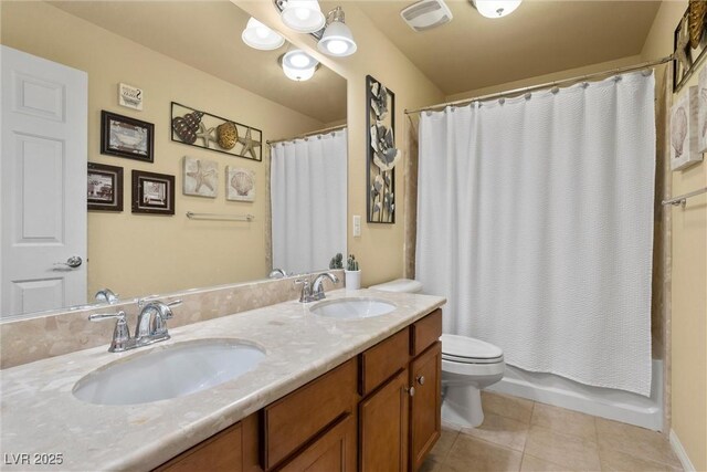 full bathroom featuring toilet, double vanity, a sink, and tile patterned flooring