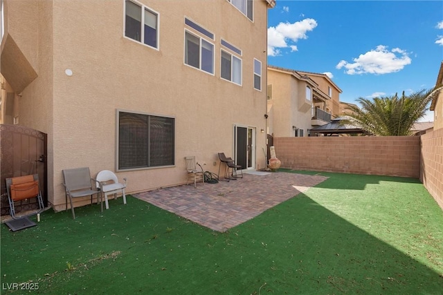 back of house with a patio area, a fenced backyard, a yard, and stucco siding