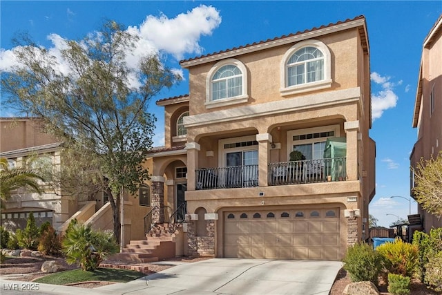 mediterranean / spanish-style home featuring concrete driveway, a balcony, stucco siding, and an attached garage