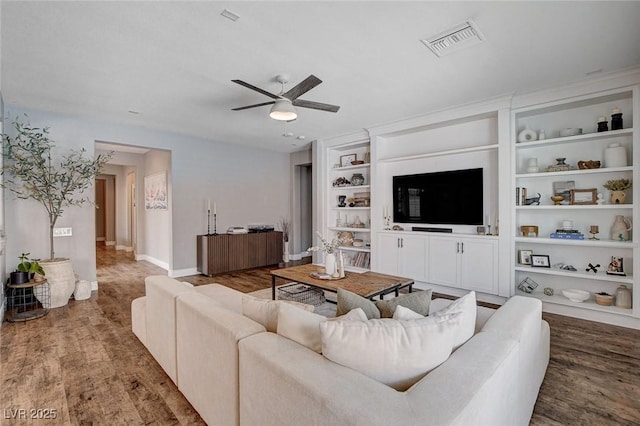 11342 Early Sun Ct, Las Vegas, NV 89135 - living room featuring visible vents, built in shelves, baseboards, ceiling fan, and wood finished floors