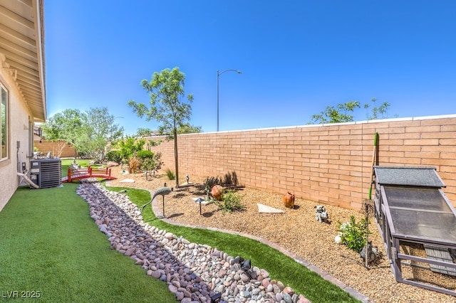 view of yard with central air condition unit and a fenced backyard