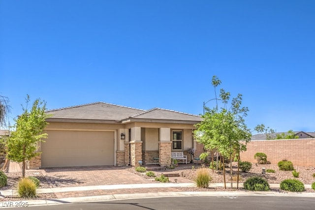 view of front of home with a tiled roof, stucco siding, decorative driveway, fence, and a garage