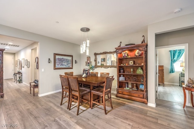dining room featuring visible vents, light wood-style flooring, a chandelier, and baseboards