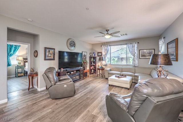 living area with baseboards, light wood-style flooring, visible vents, and ceiling fan