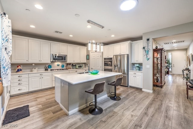 kitchen with visible vents, a sink, light wood-style floors, white cabinetry, and stainless steel appliances