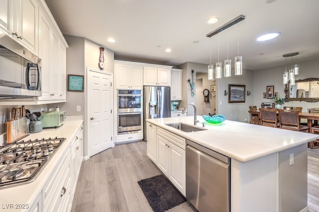 kitchen featuring a sink, light wood finished floors, white cabinetry, and stainless steel appliances